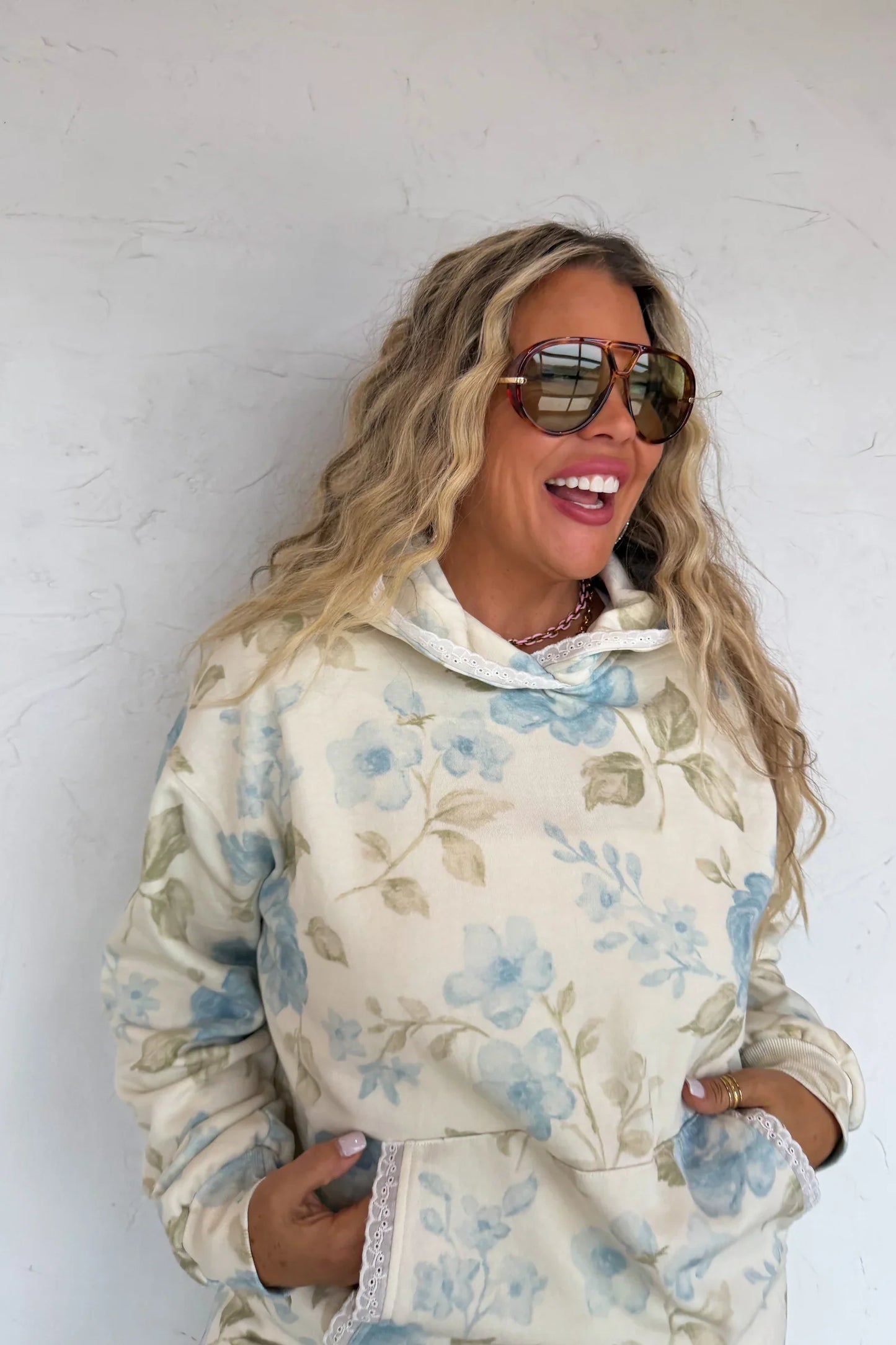 Woman wearing a blue floral hoodie against a white wall