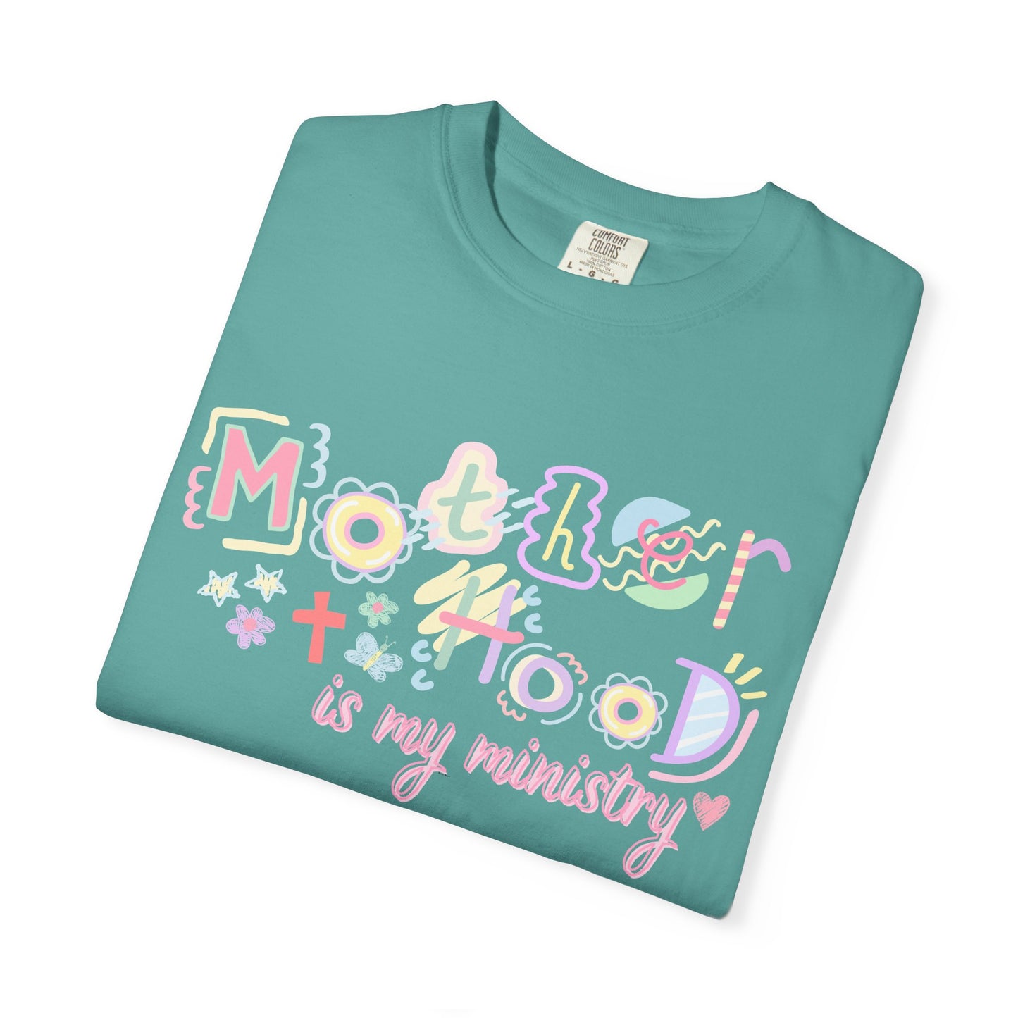 Teal t-shirt with colorful text "motherhood is my ministry" design on a white background
