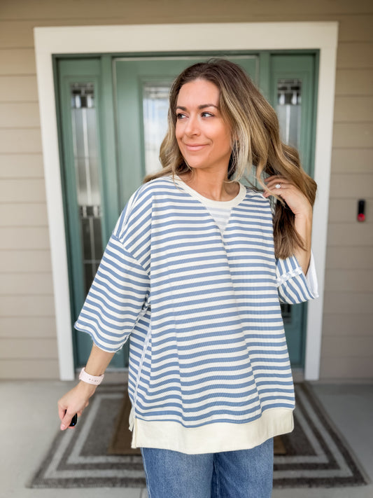 Woman wearing a blue and white striped oversized french terry shirt & jeans. 
