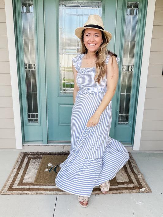 Woman in a blue and white striped dress standing in front of a teal door.