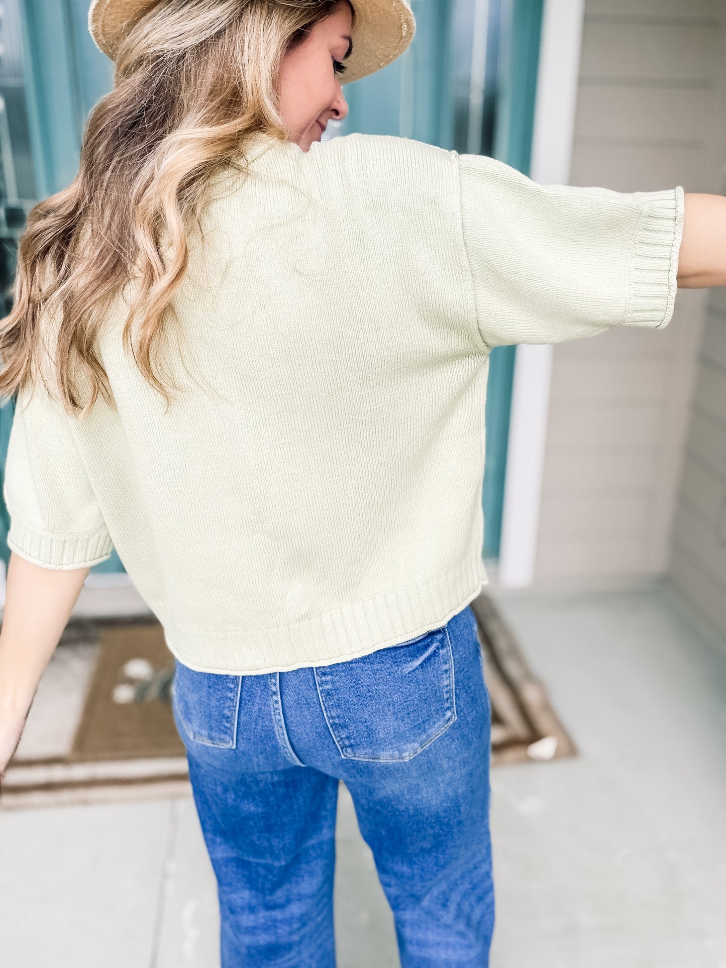 Woman wearing a light green knit sweater top backview. 