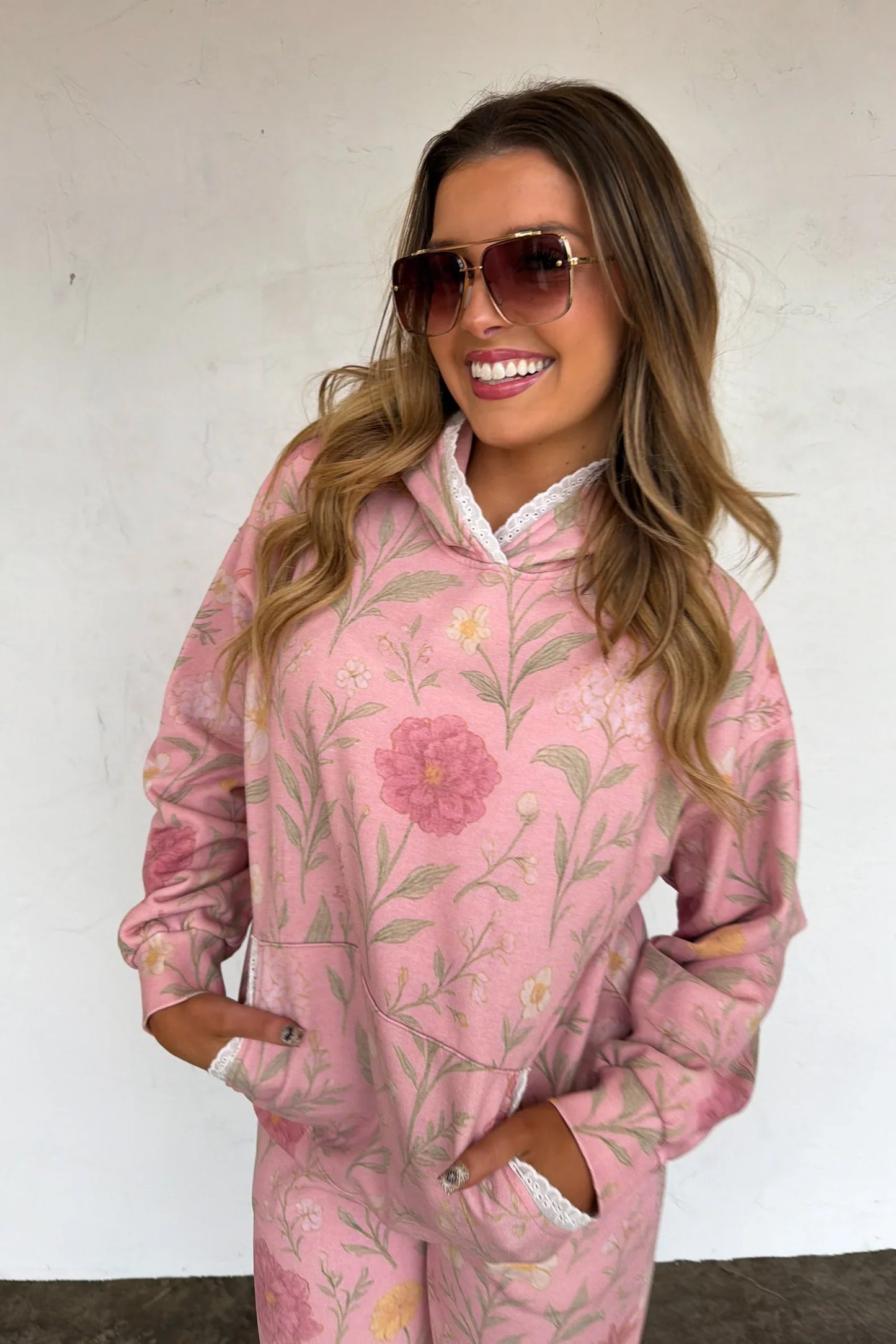 Woman wearing a pink floral hoodie and pants against a white background