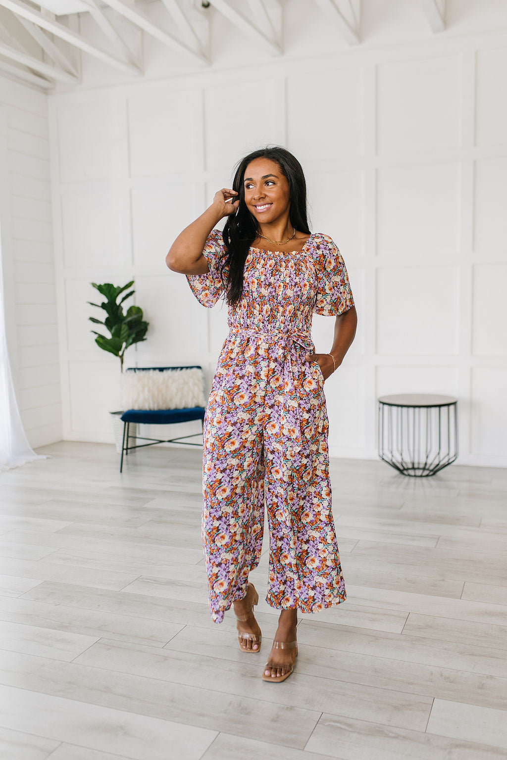 Woman wearing a floral jumpsuit in a minimal white room