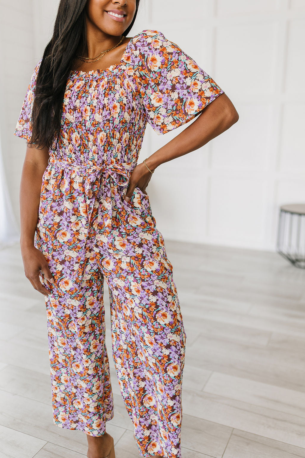 Woman wearing a floral jumpsuit in a minimal indoor setting