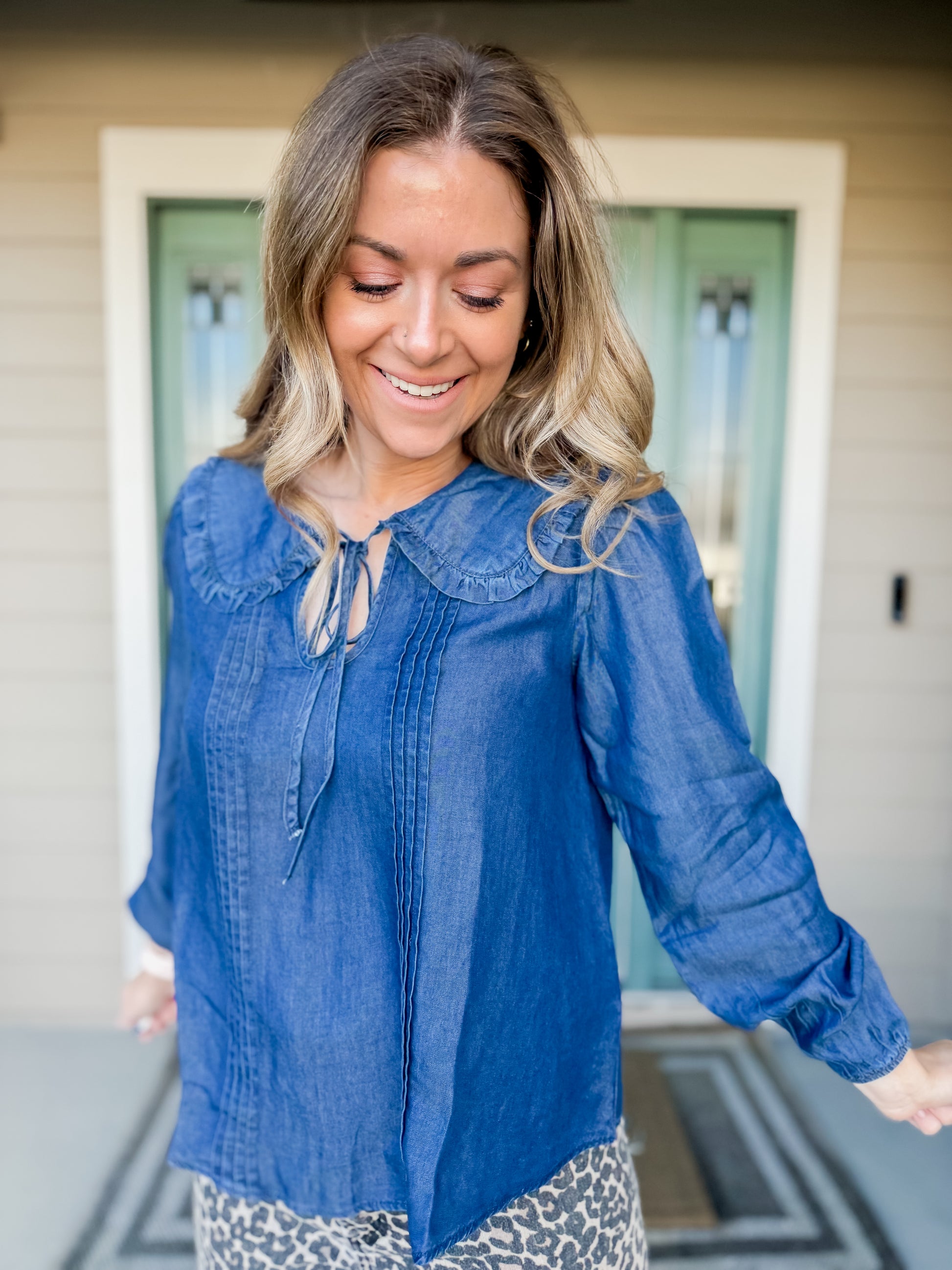 Woman wearing a blue blouse with a collar, standing outdoors. called Cerulean collared blouse. 