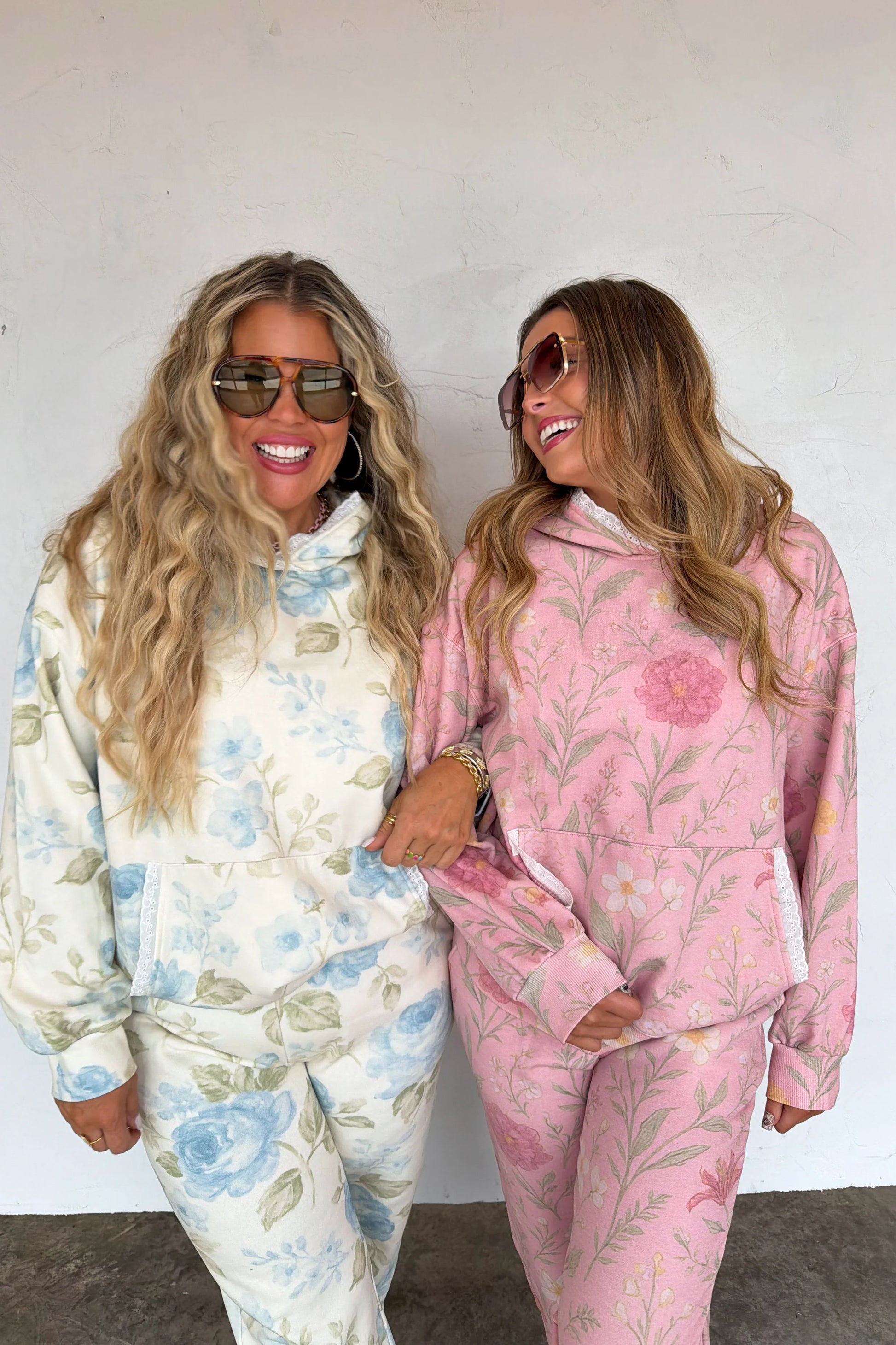 Two women wearing floral pajama sets against a white background