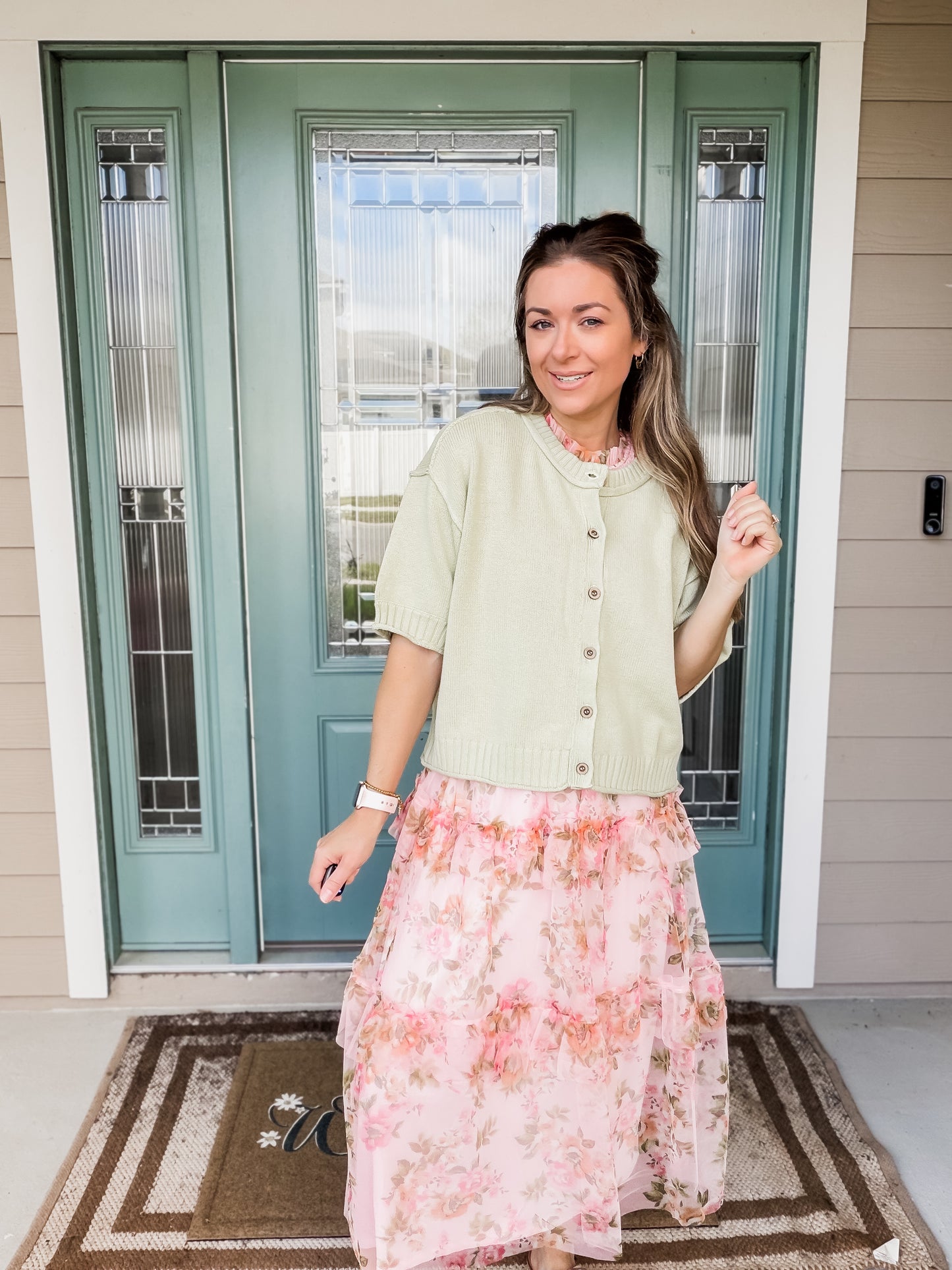 Woman wearing a light green knit sweater top layered of springtime soiree dess. 