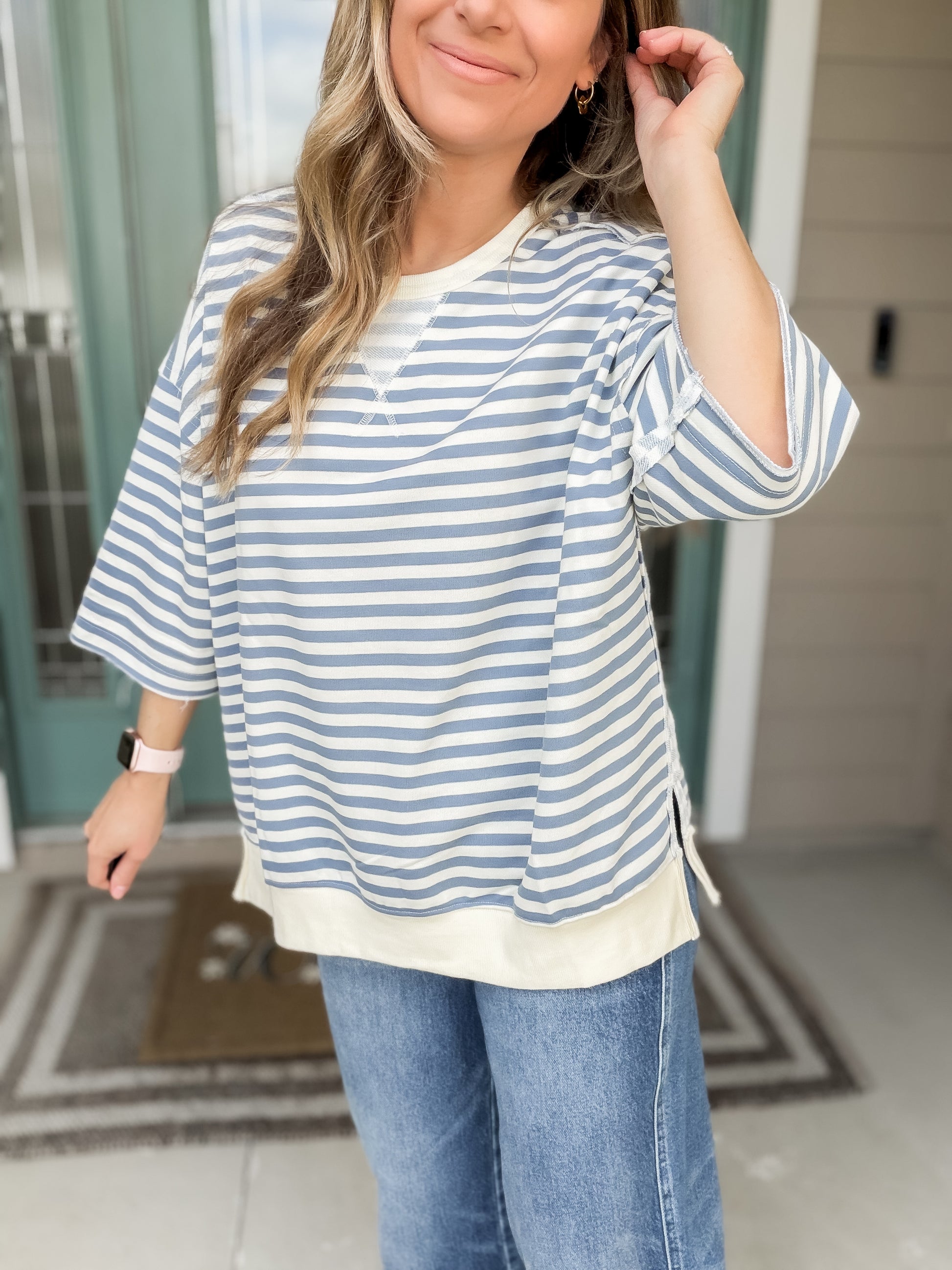 Woman wearing a blue and white striped oversized french terry shirt & jeans. 