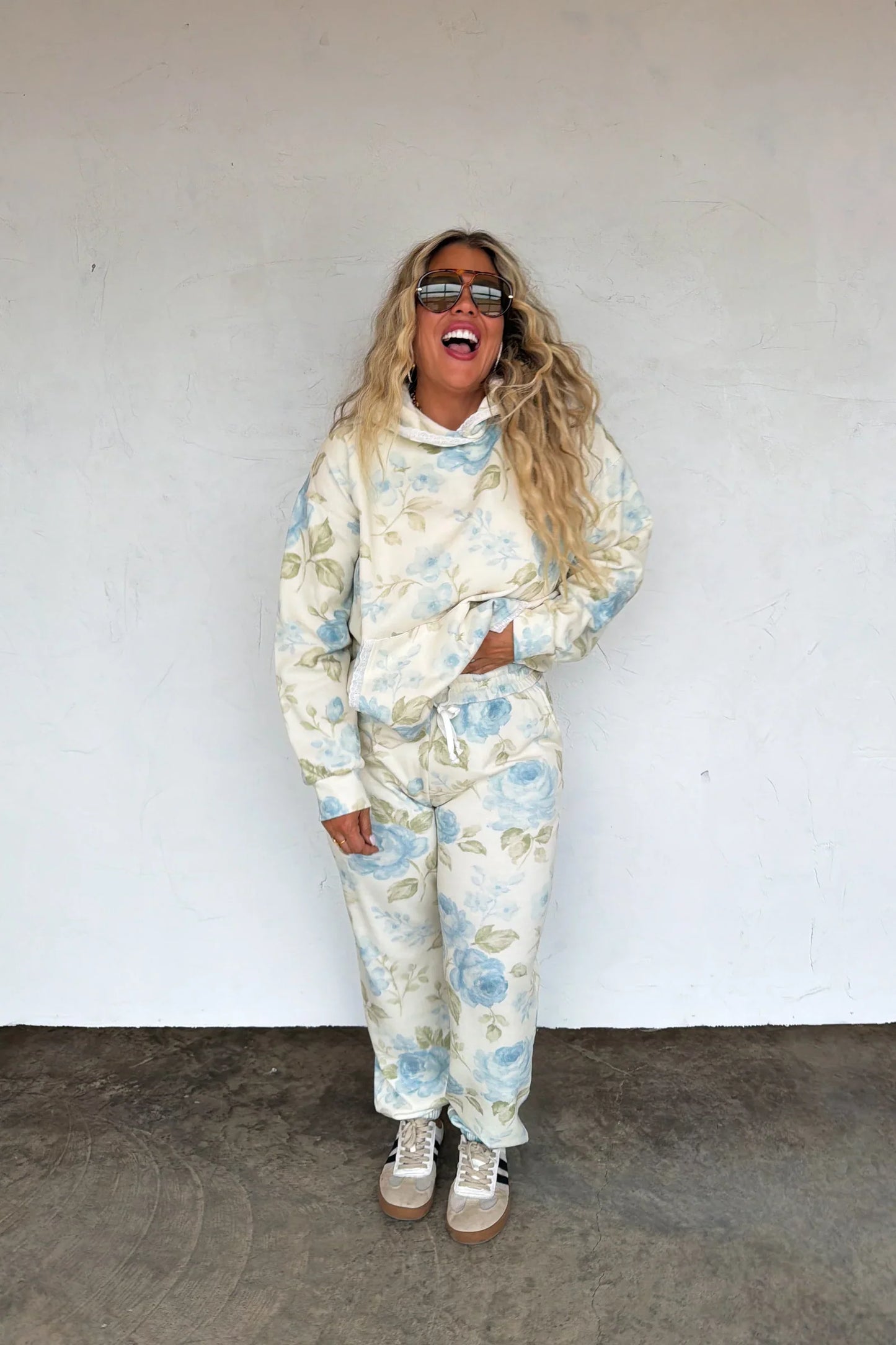 Person wearing a blue toile loral tracksuit against a white wall