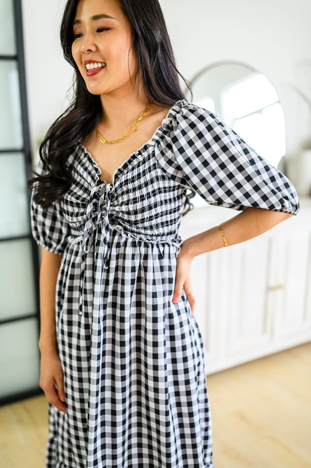 Woman wearing a black and white checkered dress indoors.