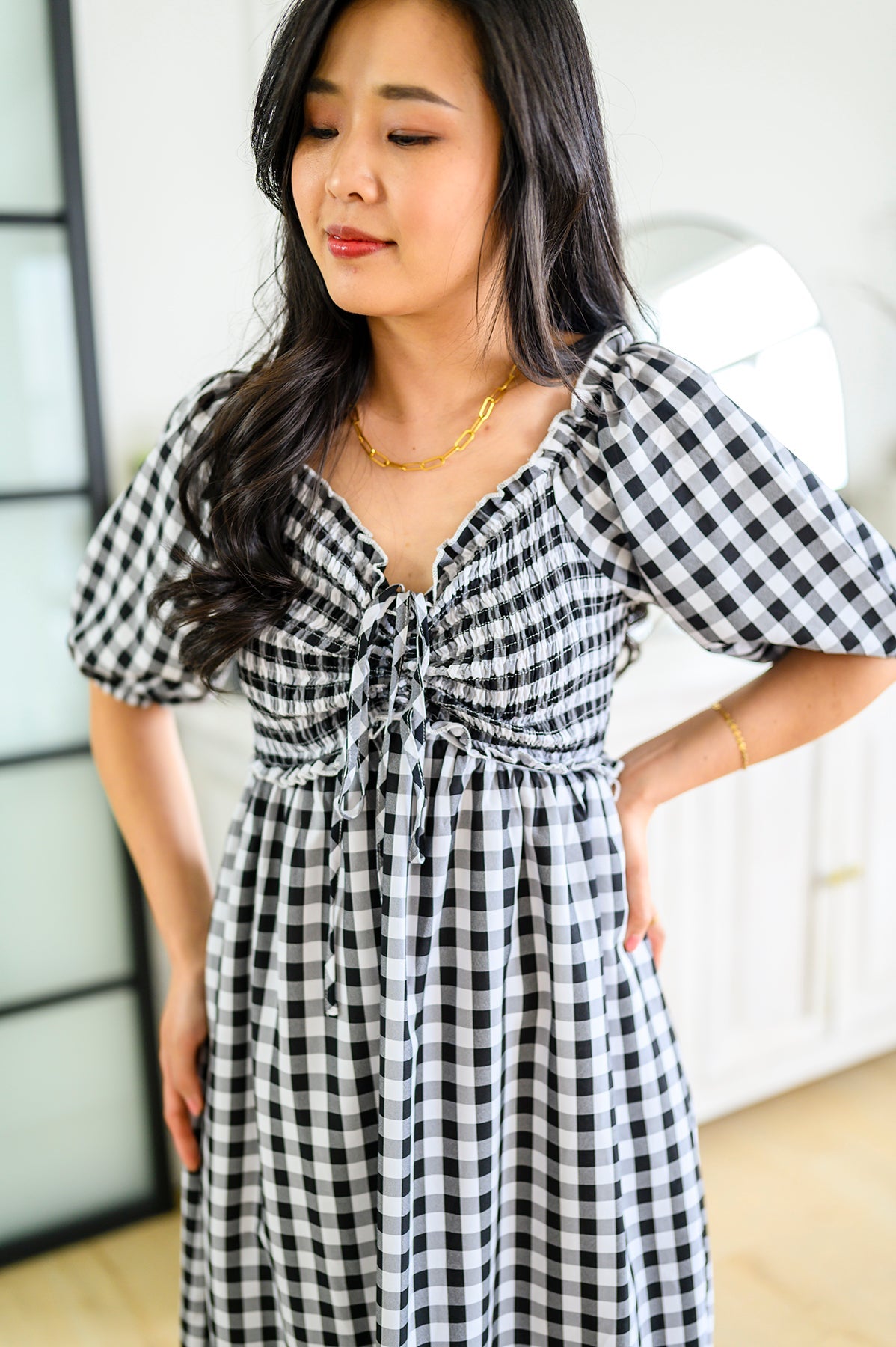 Woman wearing a black and white checkered dress indoors.