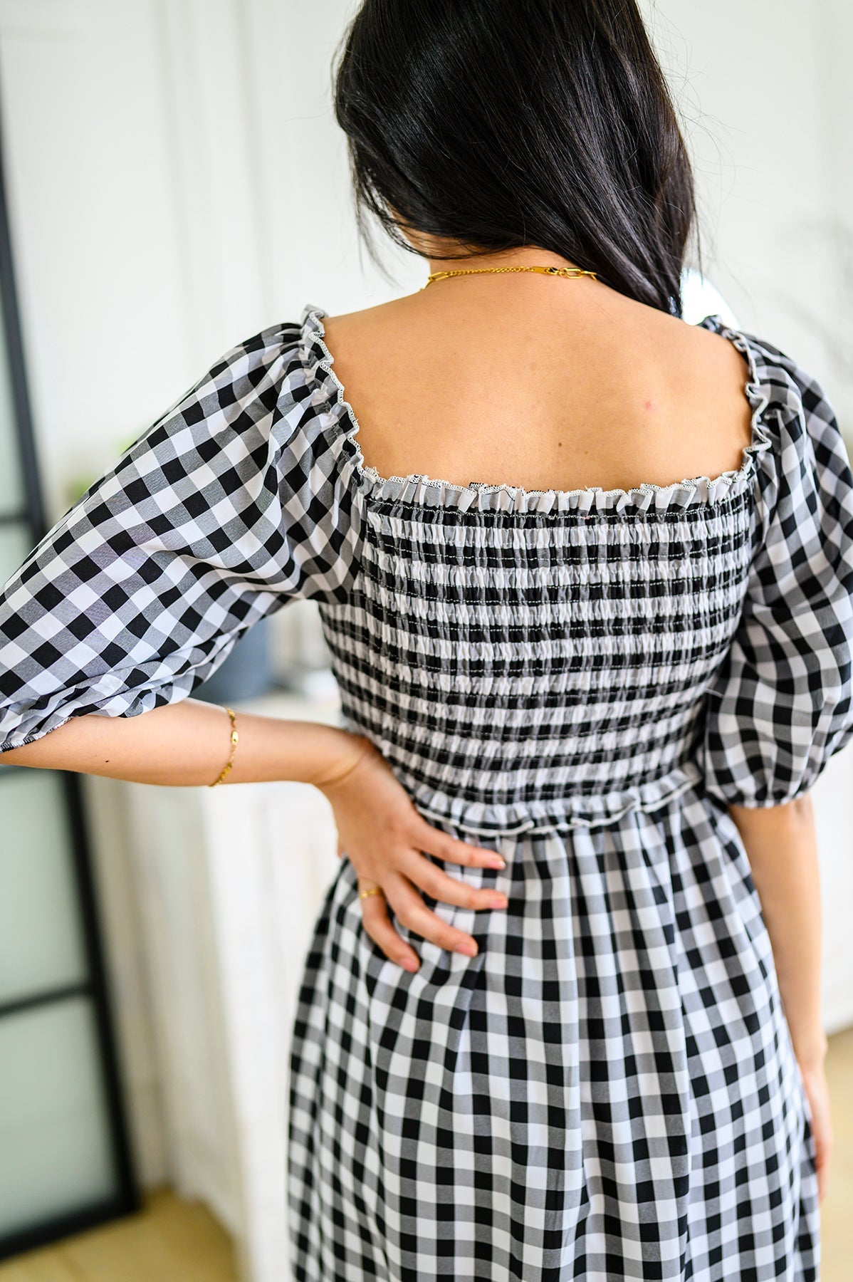 Person wearing a black and white checkered dress back view with a blurred background