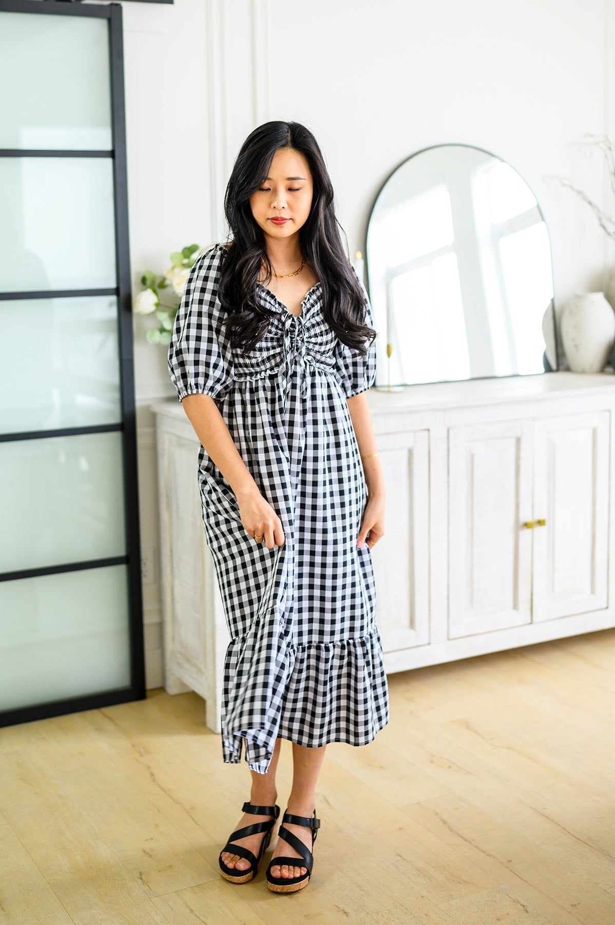girl wearing a black & white colored gingham midi dress in a home