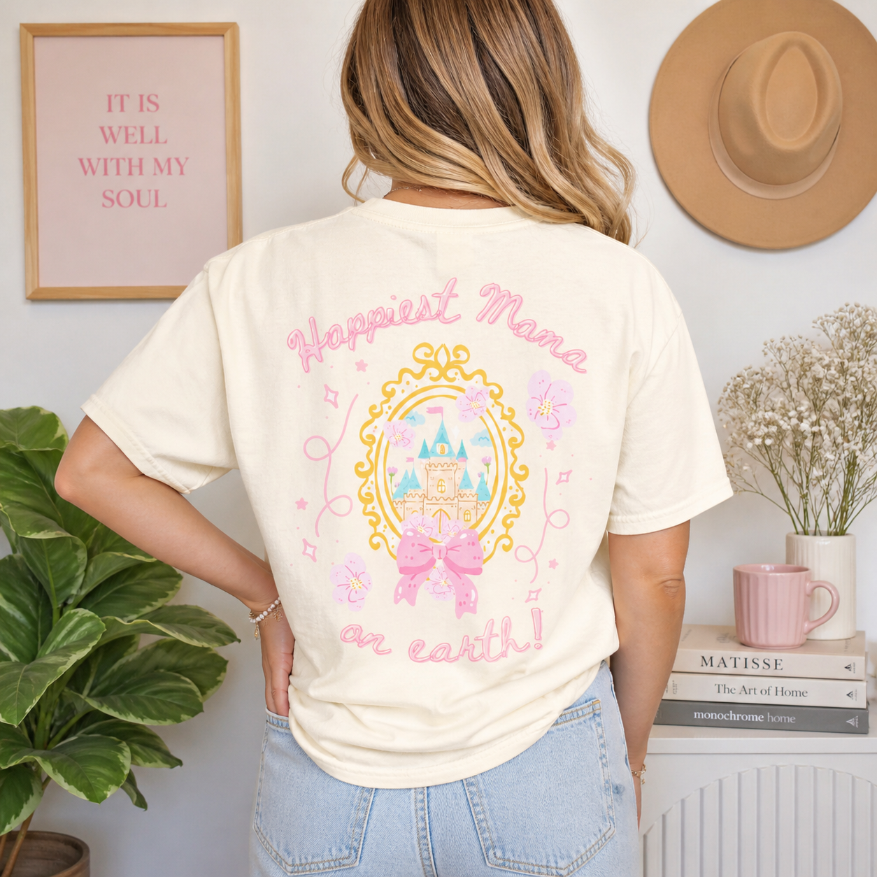 Person wearing a t-shirt with 'Happiest Mama on earth' design in a home setting.