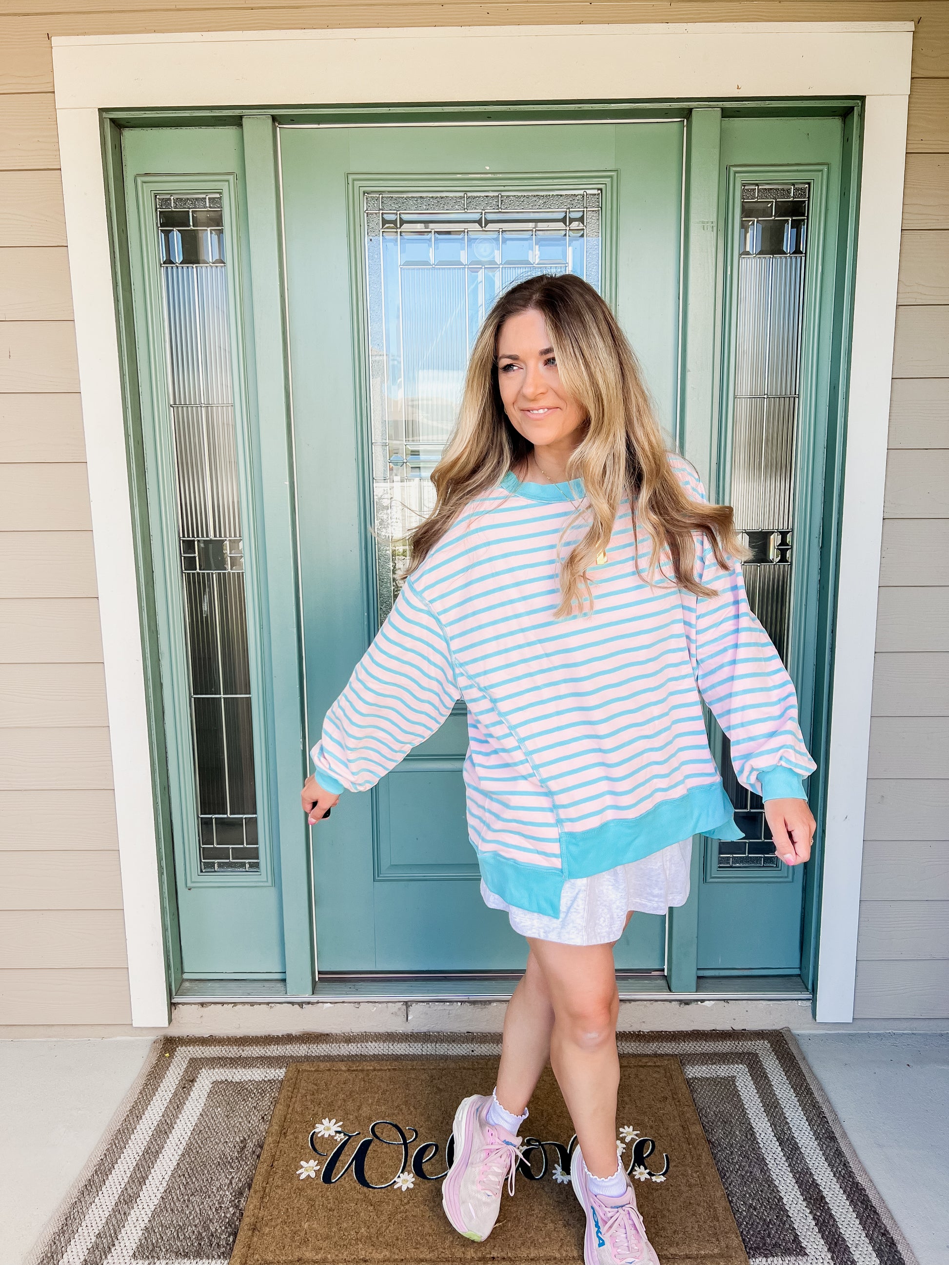 Woman wearing a striped dress standing in front of a green door.