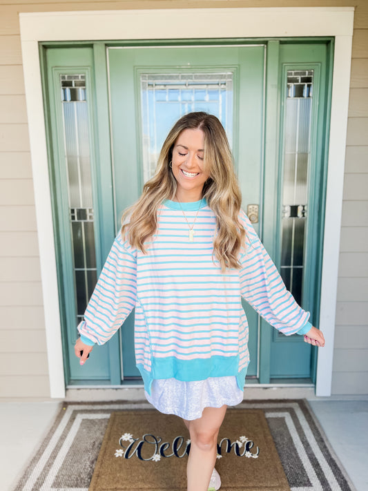 Woman wearing a striped dress standing in front of a teal door.