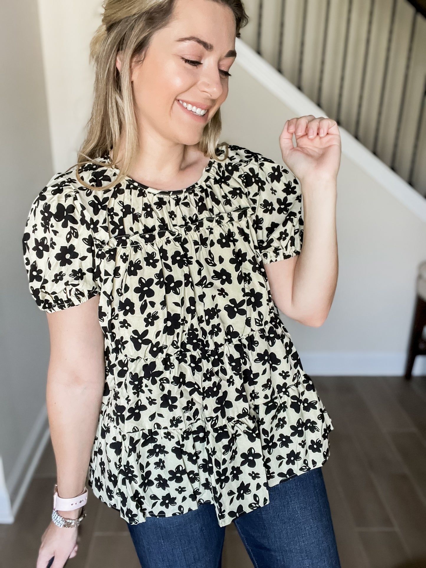 Blair flower blouse with black flowers and tan background with short sleeve tiered design. 